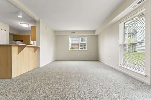 An enlarged living room with a carpeted floor and a window with blinds at Fieldstream Apartment Homes in IA 50023