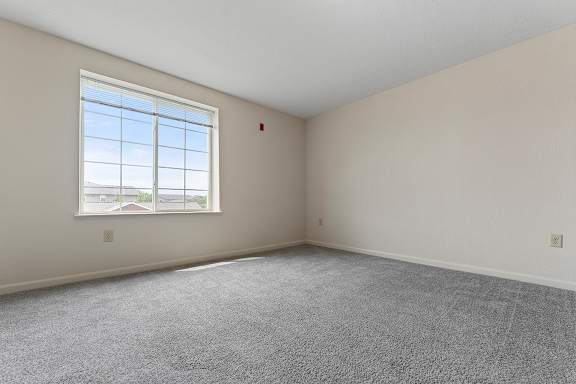 A bedroom with a large window and carpeted floor at Fieldstream Apartment Homes, Iowa