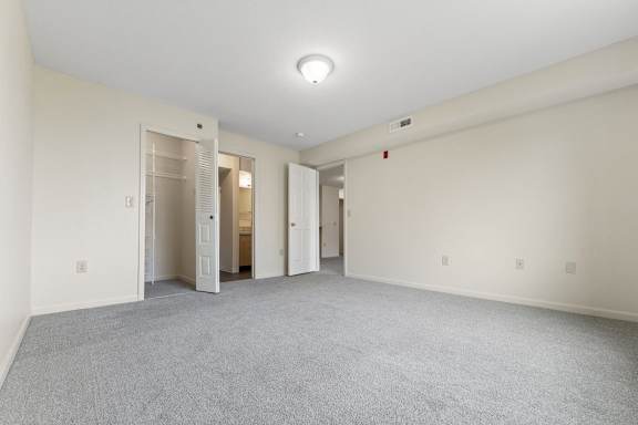 A large master room with carpeted floor, attached bathroom, and a walk-in closet with organizers at Fieldstream Apartment Homes, Iowa