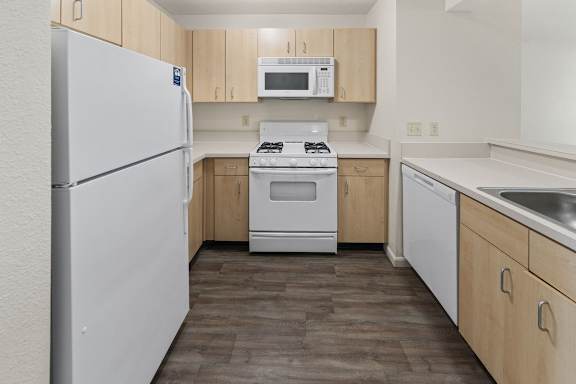 A kitchen with a white refrigerator, microwave, stove, and dishwasher at Fieldstream Apartment Homes, Iowa
