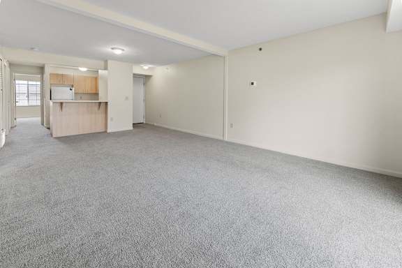 A large, empty dining room with a grey carpet at Fieldstream Apartment Homes, Iowa