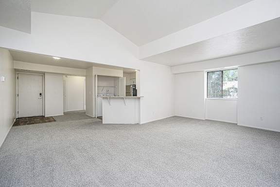 Empty living room with a cathedral ceiling and carpet at Foxwood and The Hermitage in Portage, MI