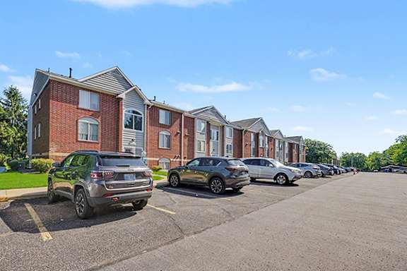A parking lot with cars and apartment buildings in the background at Foxwood and The Hermitage, Portage, Michigan