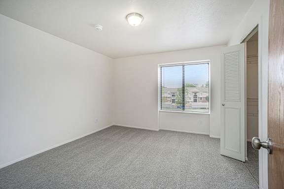A bedroom with a carpeted floor, a window and walk-in closet at Glenn Valley Apartments, Battle Creek, MI, 49015