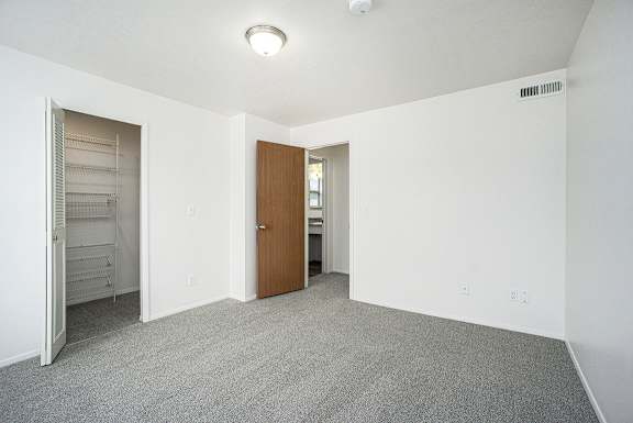 A bedroom with a walk-in closet with wardrobe organizers and plush carpet at Glenn Valley Apartments, Battle Creek, MI, 49015