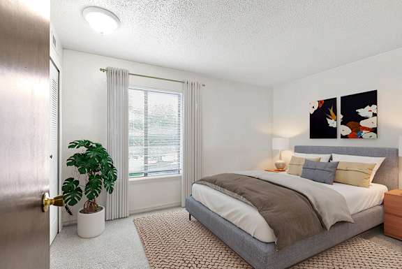 A bedroom with a large window, bed, and a plant at Granada Apartments, Jackson, 49202
