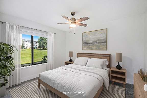 A bedroom with a large bed, a ceiling fan, and a window at Green Ridge Apartments, Grand Rapids, 49544