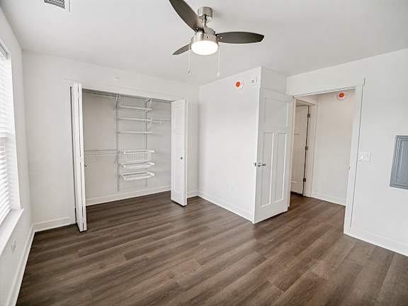 A bedroom with a ceiling fan and a walk-in closet with wardrobe organizers at The Grove Apartment Homes in Lincoln, NE