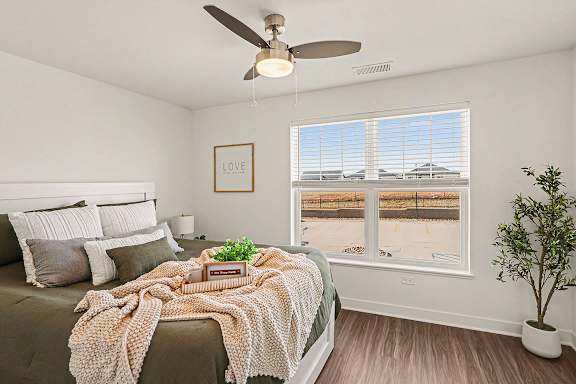 A bedroom with a bed, large windows and a ceiling fan at The Grove Apartment Homes, Nebraska