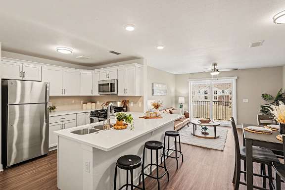A kitchen with white cabinets and a stainless steel refrigerator at The Grove Apartment Homes, Nebraska