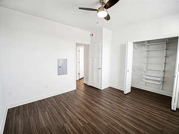 A bedroom with a ceiling fan and a walk-in closet with wardrobe organizers at The Grove Apartment Homes in Lincoln, NE