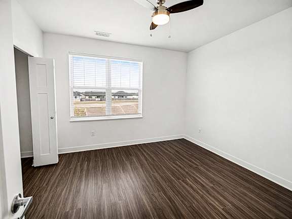 A bedroom with a ceiling fan, a large closet and window at The Grove Apartment Homes in Lincoln, NE