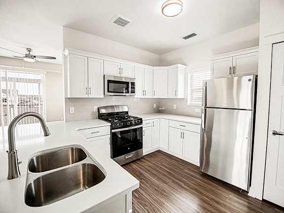 A modern kitchen with stainless steel appliances and white cabinets at The Grove Apartment Homes in Lincoln, NE