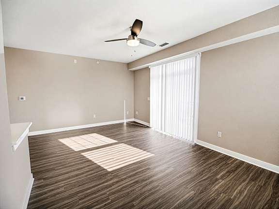A living room with a ceiling fan and hard-surface flooring at The Grove Apartment Homes in Lincoln, NE