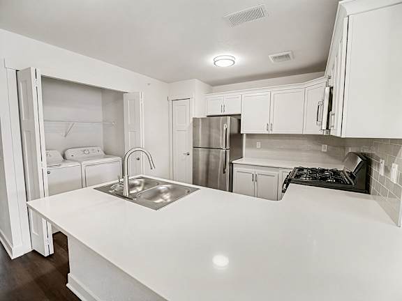A kitchen with white cabinets and a washer/dryer at The Grove Apartment Homes in Lincoln, NE