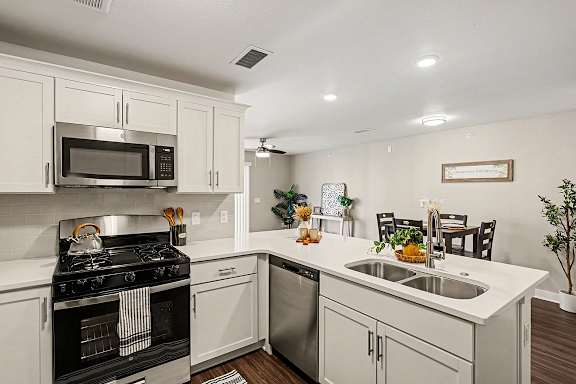 A modern kitchen with white cabinets and a breakfast bar at The Grove Apartment Homes, Nebraska
