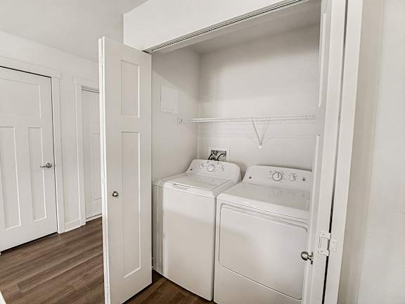 A white, full-size washing machine and dryer in a small laundry area at The Grove Apartment Homes in Lincoln, NE