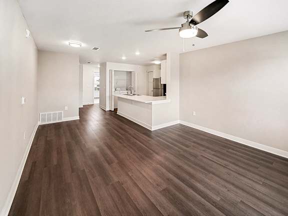 A living room with a ceiling fan and hard-surface flooring at The Grove Apartment Homes in Lincoln, NE