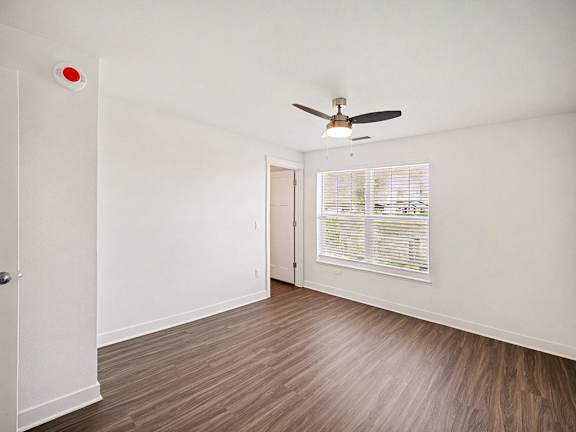 A bedroom with a ceiling fan and a window with blinds at The Grove Apartment Homes in Lincoln, NE