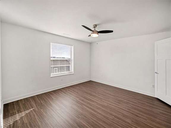 A spacious bedroom with a ceiling fan and a large window at The Grove Apartment Homes in Lincoln, NE