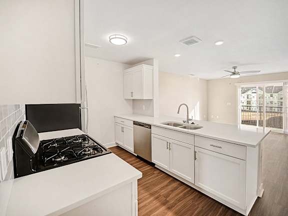 A modern kitchen with white cabinets and a breakfast bar at The Grove Apartment Homes in Lincoln, NE