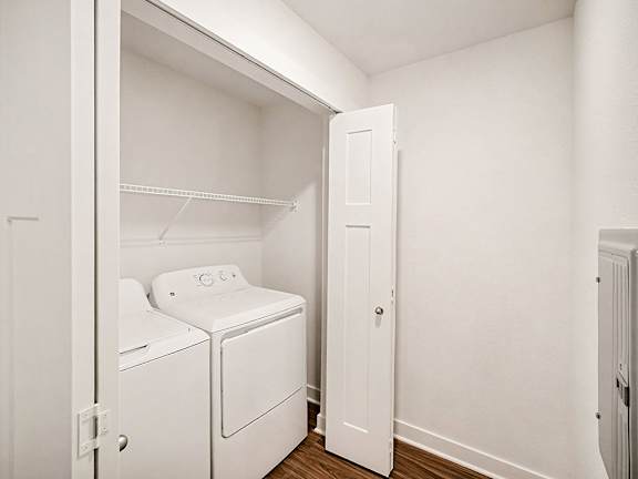 A full-size washer and dryer with a shelf above at The Grove Apartment Homes in Lincoln, NE