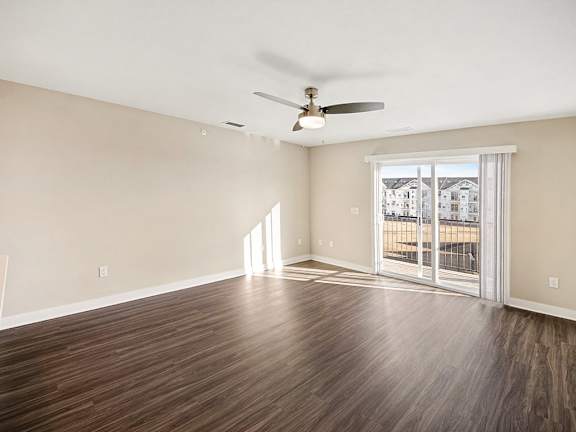 A living room with a ceiling fan and hard-surface floors at The Grove Apartment Homes in Lincoln, NE