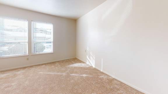 A bedroom with a carpeted floor and a window with blinds at Gull Prairie/Gull Run Apartments and Townhomes, Kalamazoo, Michigan