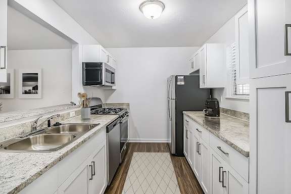A kitchen with white shaker-style cabinets and stainless steel appliances at Gull Prairie/Gull Run Apartments and Townhomes, Kalamazoo, MI