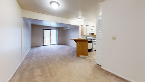 an empty living room and kitchen with a counter
