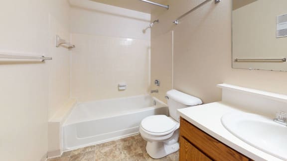 a bathroom with a toilet and a tub and a sink at Hampton Lakes Apartments in Walker, MI 49534