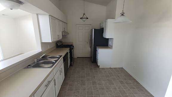a kitchen with white cabinets and a sink and a refrigerator