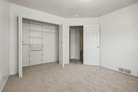 A white room with a carpeted floor and a white door.