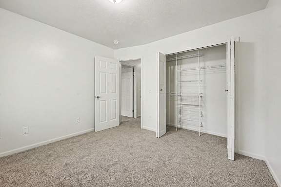 A white room with a carpeted floor and a white door.