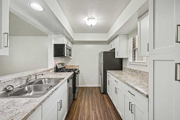 A kitchen with a sink, stove, and refrigerator.
