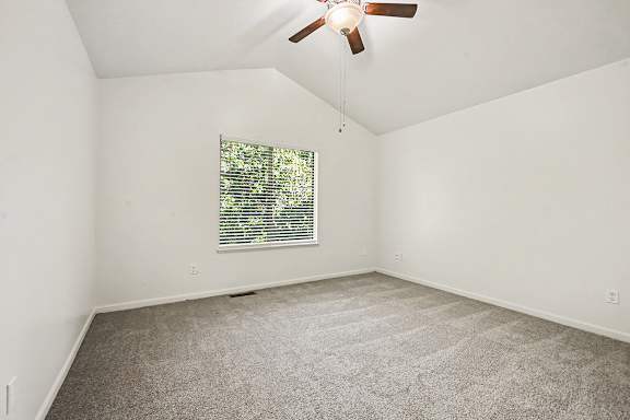A room with a ceiling fan and a window with blinds.