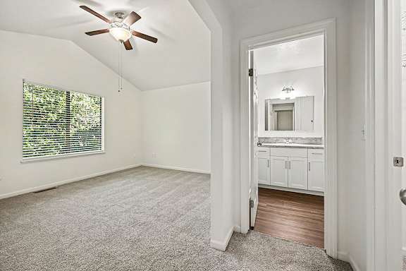 A room with a ceiling fan and a window with blinds.
