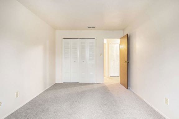 an empty living room with a door to a closet at Hickory Village Apartments, Mishawaka, IN