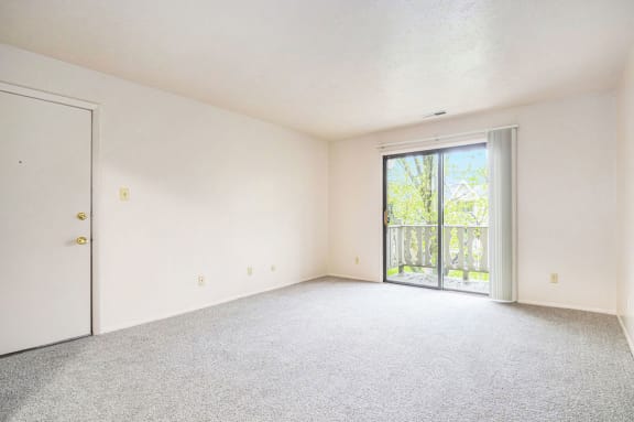 an empty living room with a door to a balcony at Hickory Village Apartments, Mishawaka