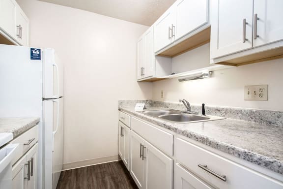a kitchen with white cabinets and a sink and refrigerator at Hickory Village Apartments, Indiana, 46545