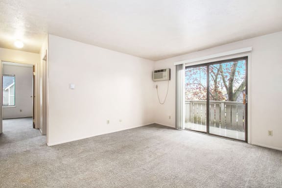 an empty living room with a sliding glass door to a patio at Hickory Village Apartments, Mishawaka, Indiana