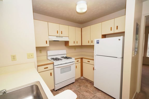 a kitchen with white appliances and white cabinets at The Highlands Apartments, Elkhart