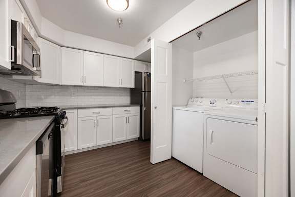 A kitchen with white cabinets and a washer and dryer