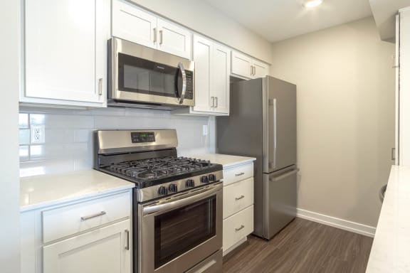 a kitchen with white cabinets and stainless steel appliances at Hillside Apartments, Wixom