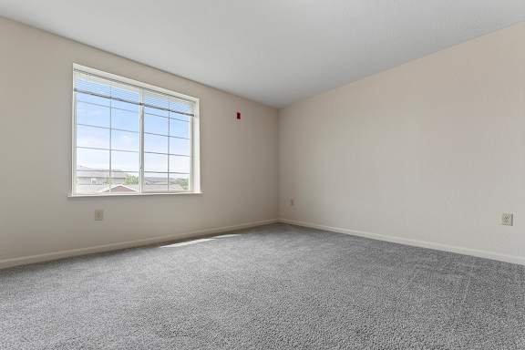 A bedroom with a large window and carpeted floor at Hunters Pond Apartment Homes, Champaign, IL, 61820