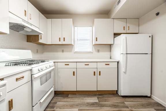 A white kitchen with a refrigerator, oven, and cabinets at Huntington Cove Apartments, Merrillville, IN