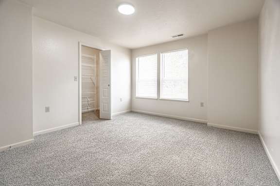 A room with a carpeted floor and a door leading to another room at Huntington Cove Apartments, Merrillville, IN