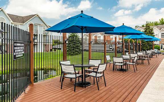 A wooden deck with chairs and umbrellas at Huntington Cove Apartments, Merrillville, IN