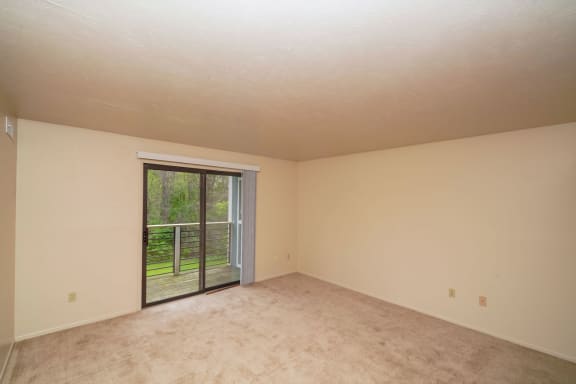 an empty living room with a sliding glass door to a patio  at Hurwich Farms Apartments, South Bend