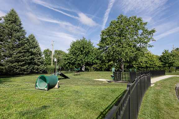 a park with green grass and trees and a black fence at Latitudes Apartments, Indianapolis, IN